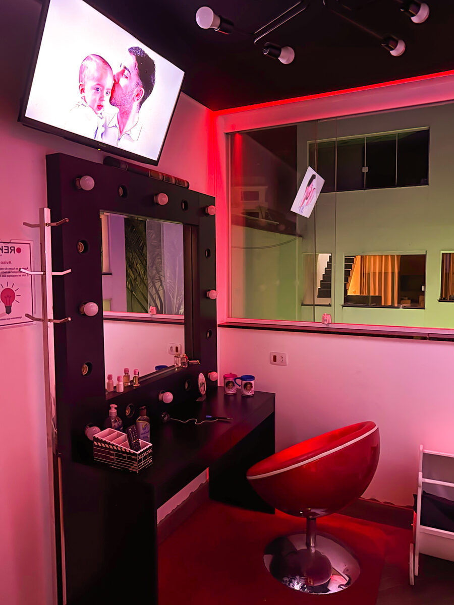 Camarim com iluminação LED magenta, espelho de penteadeira e poltrona vermelha